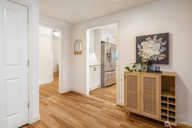 hallway featuring light wood finished floors and baseboards