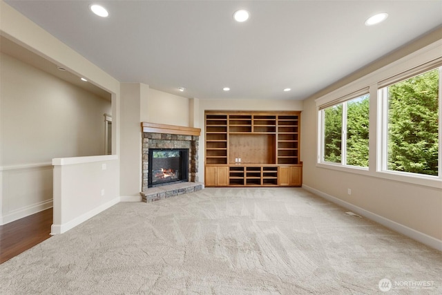 unfurnished living room with light colored carpet, a fireplace, baseboards, and recessed lighting