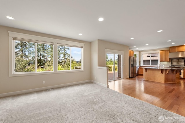 kitchen featuring baseboards, a sink, a kitchen bar, open floor plan, and stainless steel fridge
