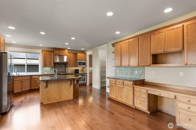 kitchen featuring a sink, tasteful backsplash, a breakfast bar area, dark wood-style floors, and appliances with stainless steel finishes