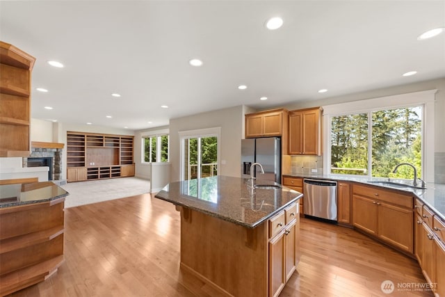 kitchen with open shelves, appliances with stainless steel finishes, a sink, and dark stone counters
