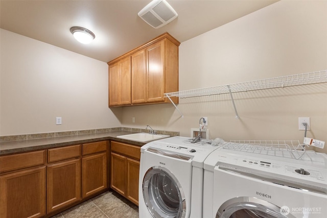 laundry room featuring a sink, cabinet space, light tile patterned flooring, visible vents, and washing machine and dryer