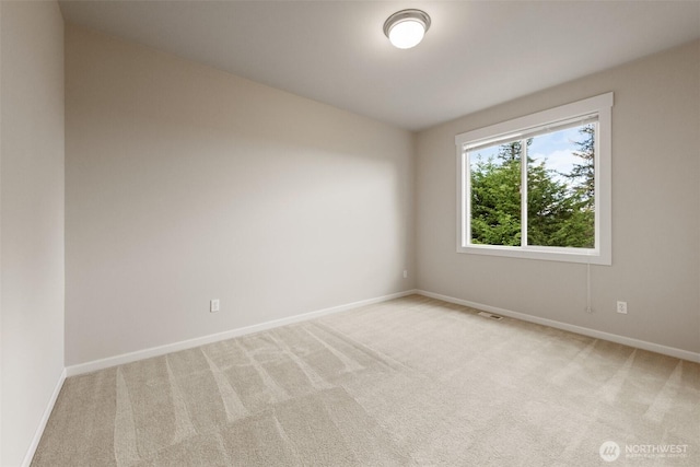 empty room with light colored carpet, baseboards, and visible vents