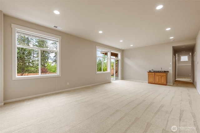 unfurnished living room with a wealth of natural light, light carpet, and recessed lighting