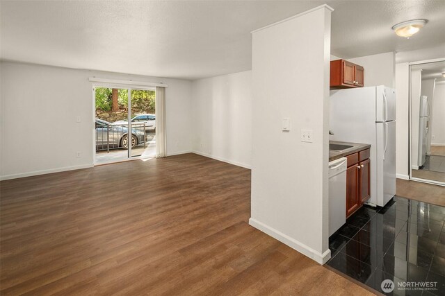 kitchen with white appliances, open floor plan, dark wood-type flooring, and baseboards