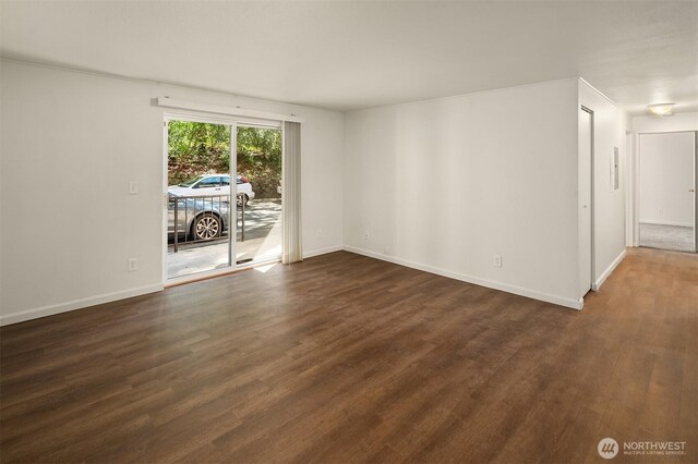 empty room with dark wood finished floors and baseboards