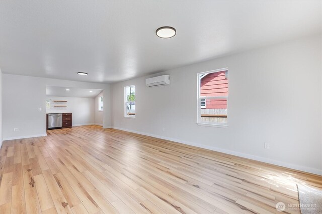 103 Madison St, Ryderwood, WA 98581 - unfurnished living room with an AC wall unit, light wood-style floors, and baseboards