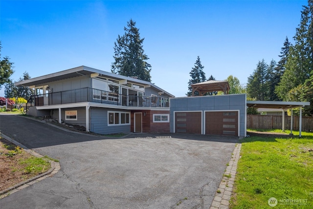 view of front of home with asphalt driveway, a carport, a balcony, and a garage