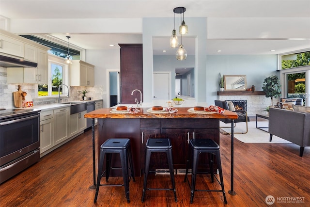 kitchen with stainless steel electric stove, under cabinet range hood, dark wood-style flooring, plenty of natural light, and recessed lighting