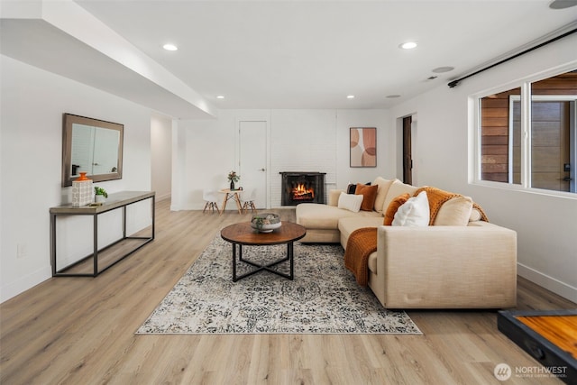 living room featuring wood finished floors, baseboards, recessed lighting, and a fireplace