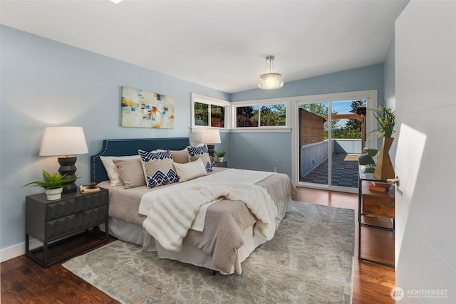 bedroom with access to exterior, multiple windows, wood finished floors, and baseboards