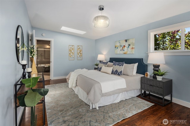 bedroom featuring wood finished floors, a skylight, baseboards, and lofted ceiling