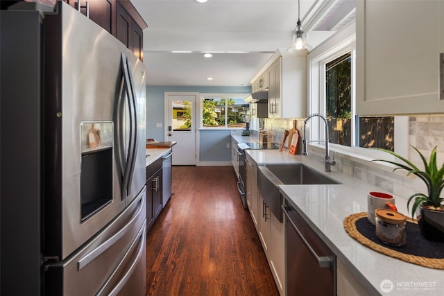 kitchen with appliances with stainless steel finishes, dark wood-type flooring, backsplash, recessed lighting, and light stone counters
