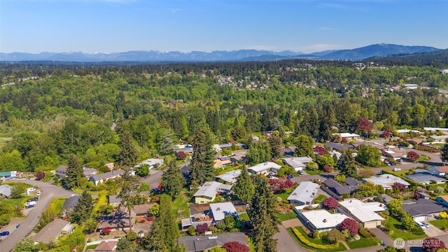 aerial view of residential area with a heavily wooded area and a mountainous background