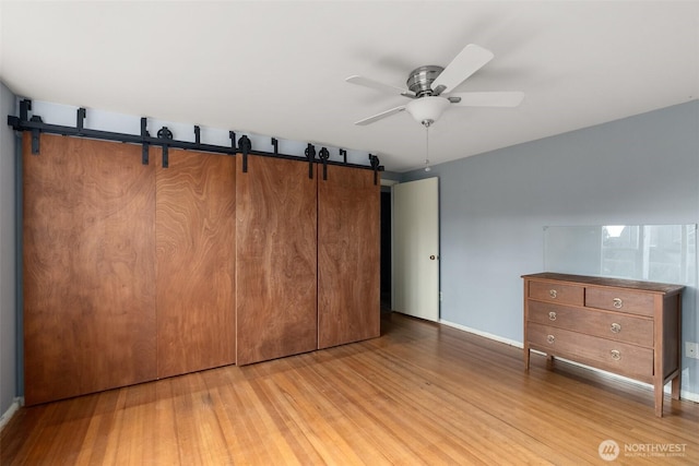 1203 Tower Ave, Raymond, WA 98577 - unfurnished bedroom featuring a barn door, light wood finished floors, and baseboards