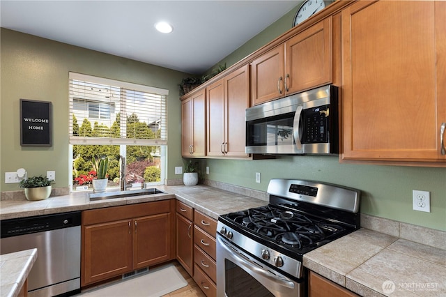 kitchen featuring appliances with stainless steel finishes, a sink, recessed lighting, and brown cabinets