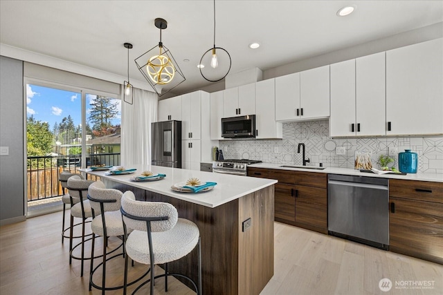 kitchen with appliances with stainless steel finishes, a center island, a sink, a breakfast bar area, and light countertops