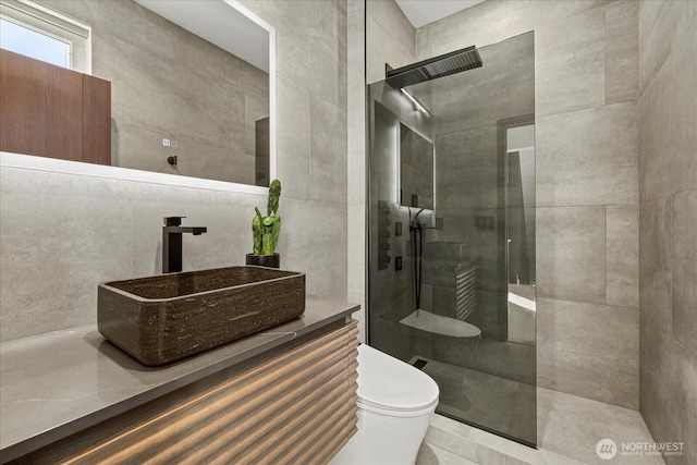 bathroom with toilet, a walk in shower, vanity, tile patterned floors, and tile walls