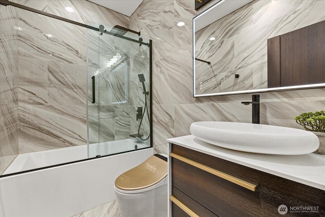 bathroom with vanity, toilet, enclosed tub / shower combo, and tile walls