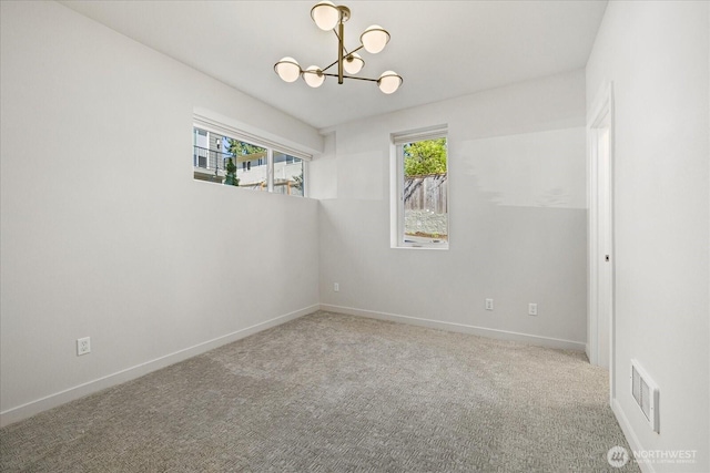carpeted spare room with a chandelier and baseboards