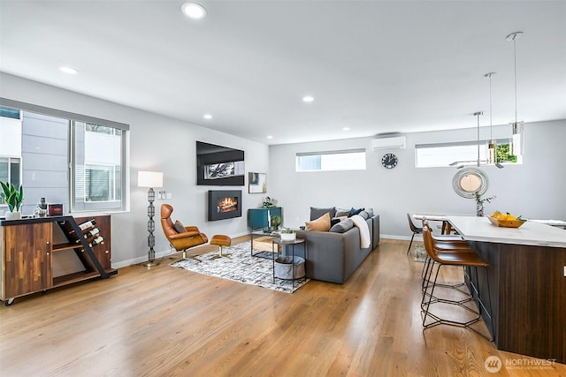 1709 NW 64th St, Seattle, WA 98107 - living room with a wall mounted AC, light wood-type flooring, baseboards, recessed lighting, and a warm lit fireplace