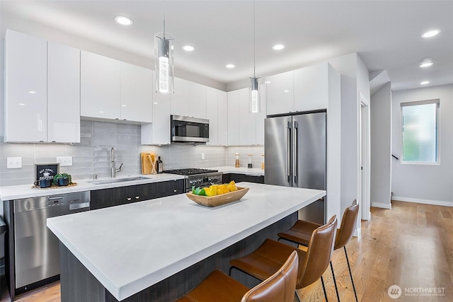 1709 NW 64th St, Seattle, WA 98107 - kitchen featuring high quality appliances, a sink, a kitchen breakfast bar, light countertops, and white cabinets