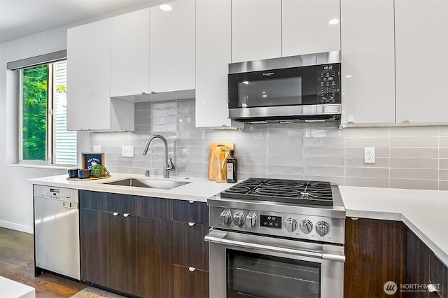 1709 NW 64th St, Seattle, WA 98107 - kitchen with stainless steel appliances, a sink, light countertops, white cabinetry, and decorative backsplash