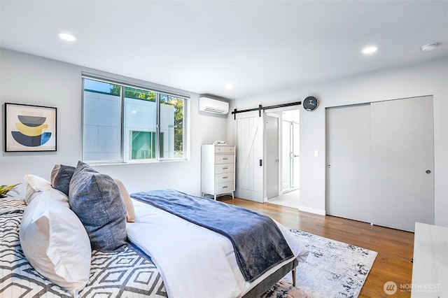 1709 NW 64th St, Seattle, WA 98107 - bedroom featuring a wall unit AC, a barn door, wood finished floors, and recessed lighting