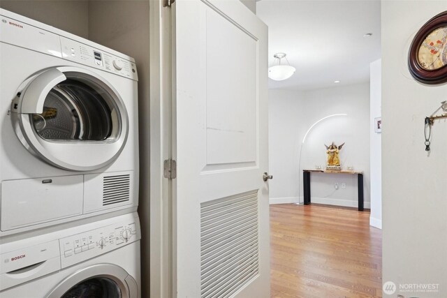 1920 4th Ave Unit 502, Seattle, WA 98101 - laundry room with stacked washing machine and dryer, light wood-style flooring, and baseboards