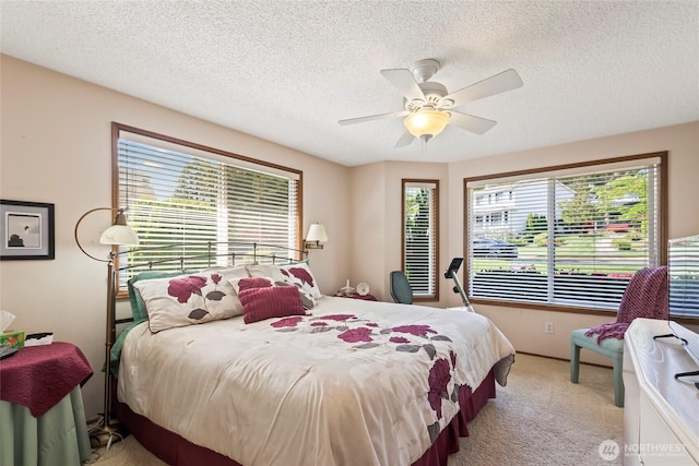 bedroom featuring light colored carpet, a textured ceiling, and ceiling fan