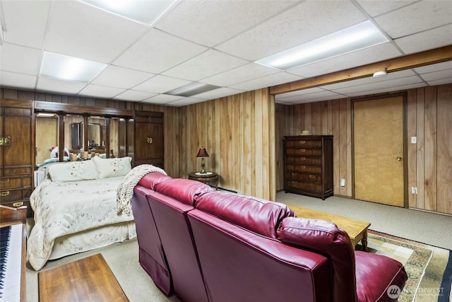 carpeted home theater featuring a paneled ceiling and wood walls