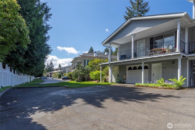 view of front facade featuring a balcony, a garage, and asphalt driveway