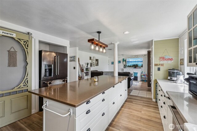 14612 Avon Allen Rd, Mount Vernon, WA 98273 - kitchen featuring ornate columns, open floor plan, glass insert cabinets, white cabinets, and light wood-style flooring