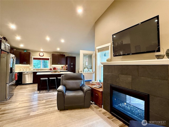 735 Dover Ct SE, Ocean Shores, WA 98569 - living area with light wood-style flooring, a tiled fireplace, high vaulted ceiling, and recessed lighting