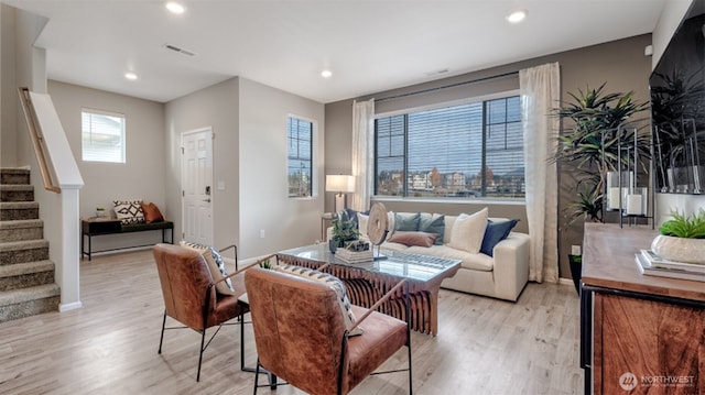living area featuring stairs, baseboards, light wood-type flooring, and visible vents