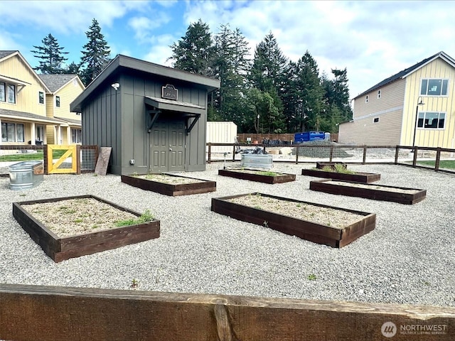 exterior space with a vegetable garden, an outbuilding, and fence