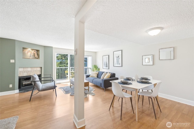 18530 52nd Ave W Unit D2, Lynnwood, WA 98037 - dining room featuring a textured ceiling, light wood-style flooring, a fireplace, and baseboards