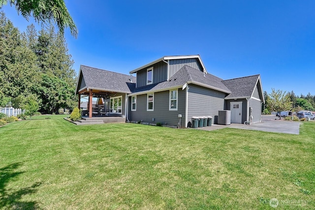 1827 Double Ditch Ct, Lynden, WA 98264 - back of property featuring a lawn, board and batten siding, a patio, roof with shingles, and central air condition unit