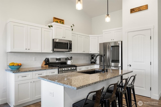 3504 Kathren Ln, Pasco, WA 99301 - kitchen with appliances with stainless steel finishes, a sink, tasteful backsplash, a kitchen breakfast bar, and stone counters