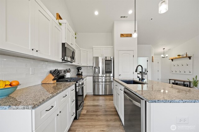 3504 Kathren Ln, Pasco, WA 99301 - kitchen featuring stainless steel appliances, a sink, white cabinetry, light wood-style flooring, and backsplash