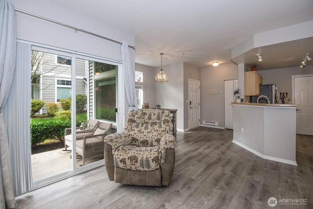 sitting room with wood finished floors, baseboard heating, and baseboards