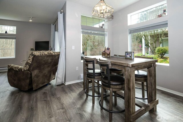 dining space featuring dark wood-style floors, a chandelier, baseboards, and a baseboard heating unit