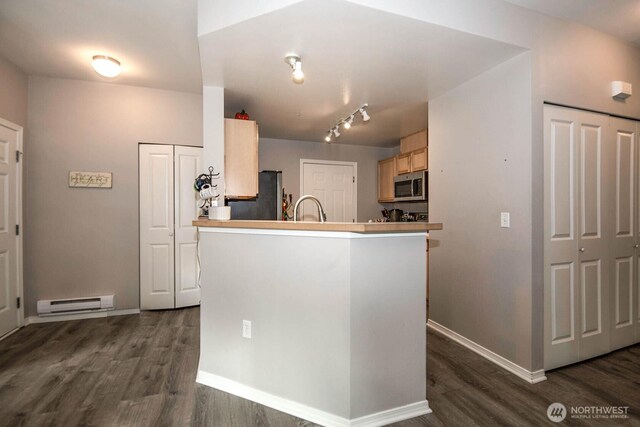 kitchen featuring stainless steel appliances, a baseboard heating unit, dark wood-style floors, and a sink