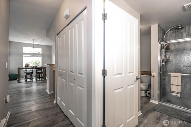 corridor featuring dark wood-type flooring and baseboards
