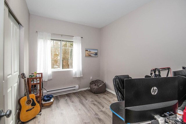 office space featuring baseboard heating, wood finished floors, and baseboards