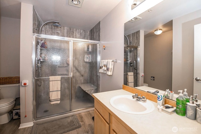 bathroom with toilet, wood finished floors, a stall shower, and vanity