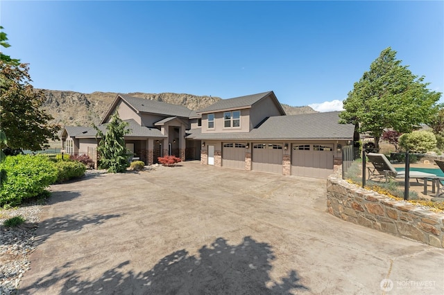 31 S Shore Dr, Orondo, WA 98843 - view of front of house featuring concrete driveway, stone siding, a mountain view, fence, and an attached garage