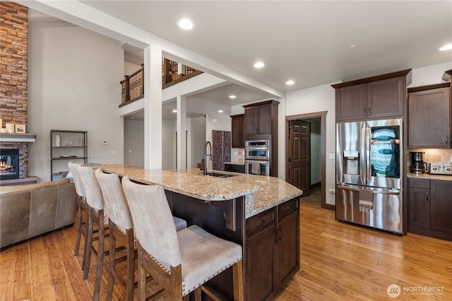 31 S Shore Dr, Orondo, WA 98843 - kitchen with appliances with stainless steel finishes, dark brown cabinets, light wood-style floors, a sink, and light stone counters
