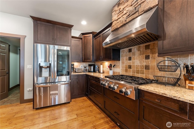 31 S Shore Dr, Orondo, WA 98843 - kitchen featuring appliances with stainless steel finishes, wall chimney exhaust hood, dark brown cabinetry, and tasteful backsplash