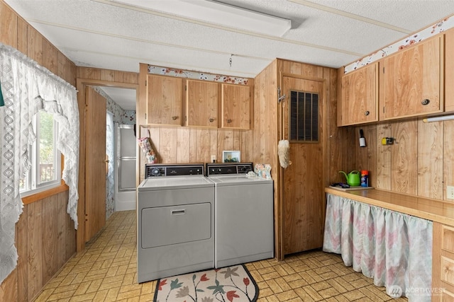 laundry room featuring washer and clothes dryer, wood walls, cabinet space, brick patterned flooring, and a textured ceiling